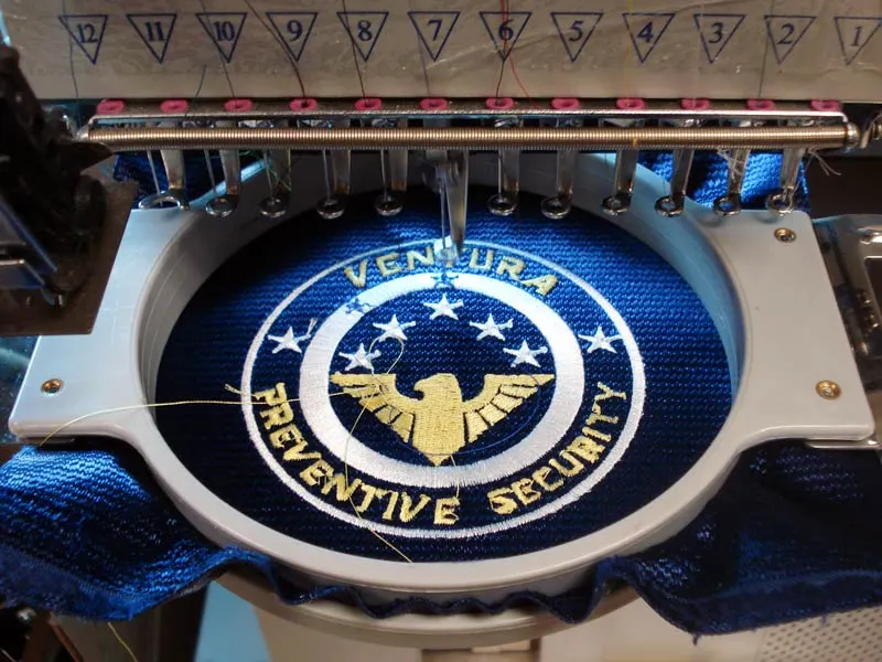 Embroidery machine stitching a security company patch