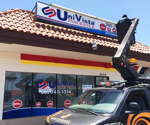 Crew on a bucket truck fitting a Univista Insurance storefront sign