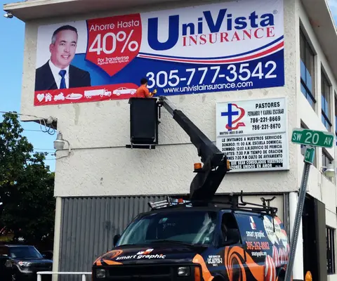 Crew on a bucket truck installing a Univista Insurance sign